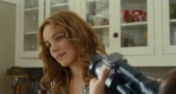 Movie still from “Aloha” (2015), directed by Cameron Crowe – A woman is holding a video camera up to her face; Close Up shot, Over the shoulder angle