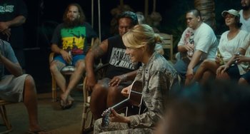 Movie still from “Aloha” (2015), directed by Cameron Crowe – A group of people sitting in a room with a guitar; Medium shot, Over the shoulder angle