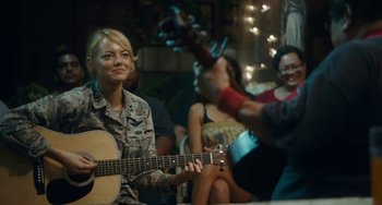 Movie still from “Aloha” (2015), directed by Cameron Crowe – A woman holding a guitar in front of other people; Medium shot, Over the shoulder angle