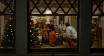 Movie still from “Aloha” (2015), directed by Cameron Crowe – A group of people sitting in a room with a christmas tree in the background; Wide shot, High angle