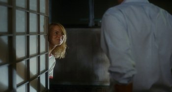 Movie still from “Aloha” (2015), directed by Cameron Crowe – A woman looking out of a window at a man in a white shirt; Medium shot, Over the shoulder angle