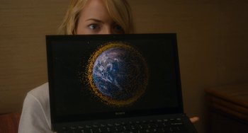 Movie still from “Aloha” (2015), directed by Cameron Crowe – A woman is hiding her face behind a computer screen; Medium shot, Overhead angle