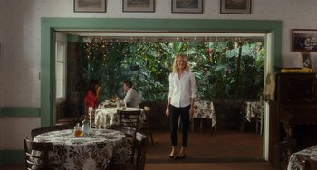 Movie still from “Aloha” (2015), directed by Cameron Crowe – A woman standing in front of a table in a restaurant; Wide shot, Over the shoulder angle