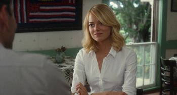 Movie still from “Aloha” (2015), directed by Cameron Crowe – A woman sitting at a table in front of an american flag; Close Up shot, Over the shoulder angle