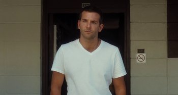 Movie still from “Aloha” (2015), directed by Cameron Crowe – A man in a white shirt standing in front of a door; Medium shot, Low angle
