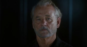 Movie still from “Aloha” (2015), directed by Cameron Crowe – An older man with gray hair wearing a black shirt; Close Up shot, Low angle