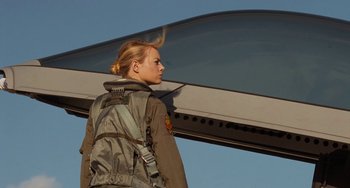 Movie still from “Aloha” (2015), directed by Cameron Crowe – A woman with a back pack standing under an airplane wing; Medium shot, Low angle