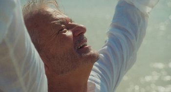 Movie still from “Aloha” (2015), directed by Cameron Crowe – An older man with a white shirt is looking up; Close Up shot, Low angle