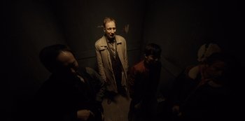 Movie still from “Fargo” (2014), created by Noah Hawley – A group of people standing in a dark room; Medium shot, High angle