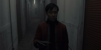 Movie still from “Fargo” (2014), created by Noah Hawley – A man holding a knife in a dark hallway; Medium shot, Low angle
