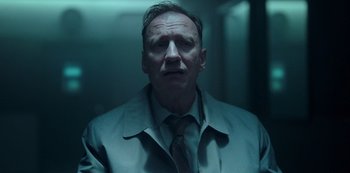 Movie still from “Fargo” (2014), created by Noah Hawley – A man wearing a suit and tie in a dark room; Close Up shot, Low angle