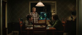 Movie still from “American Animals” (2018), directed by Bart Layton – Three people sitting at a table in front of a fish tank; Medium shot, Over the shoulder angle