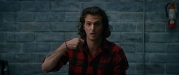 Movie still from “American Animals” (2018), directed by Bart Layton – A man in a red and black plaid shirt pointing to his face; Close Up shot, Low angle