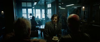Movie still from “American Animals” (2018), directed by Bart Layton – A man sitting at a table drinking coffee; Medium shot, Over the shoulder angle