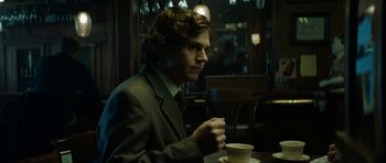 Movie still from “American Animals” (2018), directed by Bart Layton – A man sitting at a table drinking a cup of coffee; Medium shot, Low angle
