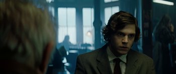 Movie still from “American Animals” (2018), directed by Bart Layton – A man in a suit and tie in front of a window; Medium shot, Over the shoulder angle