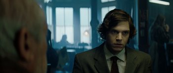 Movie still from “American Animals” (2018), directed by Bart Layton – A man in a suit and tie in front of a group of people; Close Up shot, Over the shoulder angle