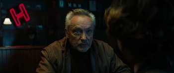 An older man is looking into the camera