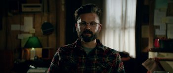 Movie still from “American Animals” (2018), directed by Bart Layton – A man with a beard wearing glasses and a plaid shirt; Close Up shot, Over the shoulder angle
