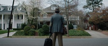 Movie still from “American Animals” (2018), directed by Bart Layton – A man standing on the side of the road holding a suitcase; Wide shot, Low angle