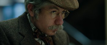 Movie still from “American Animals” (2018), directed by Bart Layton – An older man with a mustache wearing glasses and a hat; Close Up shot, Low angle