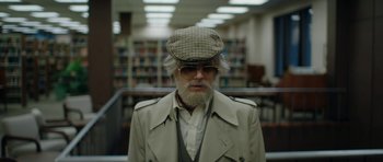 Movie still from “American Animals” (2018), directed by Bart Layton – An older man wearing a hat and glasses; Medium shot, Low angle