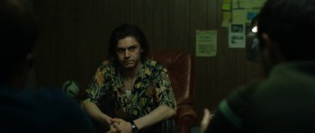 Movie still from “American Animals” (2018), directed by Bart Layton – A man sitting in a chair in front of another man; Medium shot, Over the shoulder angle