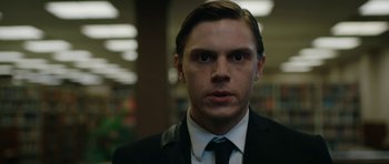 Movie still from “American Animals” (2018), directed by Bart Layton – A man wearing a suit and tie in a library; Close Up shot, Low angle