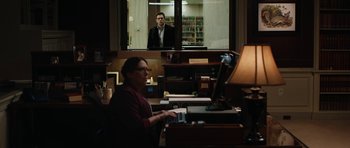 Movie still from “American Animals” (2018), directed by Bart Layton – A man is sitting at a computer in front of a window; Wide shot, Over the shoulder angle