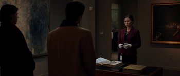 Movie still from “American Animals” (2018), directed by Bart Layton – A woman standing in front of a mirror in a room; Medium shot, Over the shoulder angle