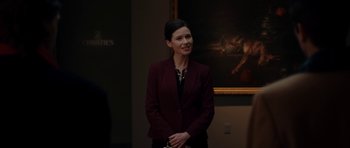Movie still from “American Animals” (2018), directed by Bart Layton – A woman standing in front of a painting in an art gallery; Medium shot, Over the shoulder angle