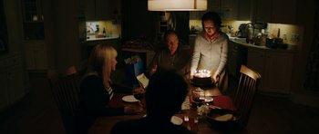 Movie still from “American Animals” (2018), directed by Bart Layton – A group of people sitting around a table with a cake; Medium shot, Over the shoulder angle