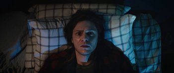 Movie still from “American Animals” (2018), directed by Bart Layton – A man laying in a bed looking up at the camera; Close Up shot, Overhead angle