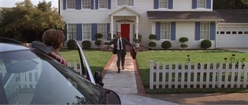 Movie still from “American Beauty” (1999), directed by Sam Mendes – A man in a suit and tie walking down a sidewalk in front of a house; Extreme Wide shot, High angle