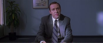 Movie still from “American Beauty” (1999), directed by Sam Mendes – A man in a suit and tie sitting at a table; Close Up shot, Over the shoulder angle