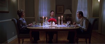 Movie still from “American Beauty” (1999), directed by Sam Mendes – A woman sitting at a dinner table in front of candles; Wide shot, High angle