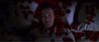 Movie still from “American Beauty” (1999), directed by Sam Mendes – A man laying in bed surrounded by red rose petals; Close Up shot, Overhead angle