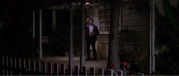 Movie still from “American Beauty” (1999), directed by Sam Mendes – A man standing on the side of the road at night holding a cell phone; Wide shot, Low angle