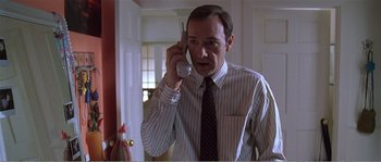 Movie still from “American Beauty” (1999), directed by Sam Mendes – A man holding a cell phone up to his ear; Close Up shot, High angle