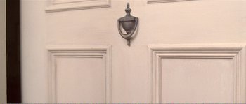 Movie still from “American Beauty” (1999), directed by Sam Mendes – A door knocker on a white door; Extreme Close Up shot, Overhead angle