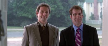 Movie still from “American Beauty” (1999), directed by Sam Mendes – A couple of men standing next to each other in suits; Medium shot, Low angle