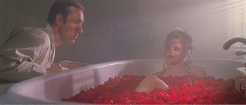 Movie still from “American Beauty” (1999), directed by Sam Mendes – A man and a woman sitting in a bath tub filled with red rose petals; Medium shot, High angle
