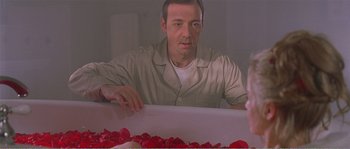 Movie still from “American Beauty” (1999), directed by Sam Mendes – A man sitting in front of a table covered with red roses; Close Up shot, Over the shoulder angle