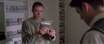 Movie still from “American Beauty” (1999), directed by Sam Mendes – A man looking at a bag of food in his hands; Medium shot, High angle