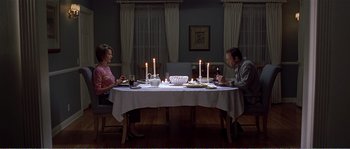 Movie still from “American Beauty” (1999), directed by Sam Mendes – A man and a woman sitting at a dinner table with lit candles; Wide shot, High angle
