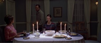 Movie still from “American Beauty” (1999), directed by Sam Mendes – A woman sitting at a table with a cake on top of it; Medium shot, High angle