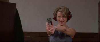Movie still from “American Beauty” (1999), directed by Sam Mendes – A woman wearing headphones and holding a gun in her hand; Medium shot, Low angle