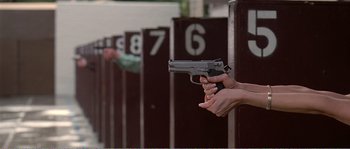 Movie still from “American Beauty” (1999), directed by Sam Mendes – A person holding a gun in front of a fence; Medium shot, Low angle
