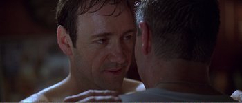 Movie still from “American Beauty” (1999), directed by Sam Mendes – A man looking into a mirror with his hands on his chest; Close Up shot, Over the shoulder angle
