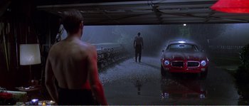 Movie still from “American Beauty” (1999), directed by Sam Mendes – A man walking in the rain next to a red car; Wide shot, Low angle
